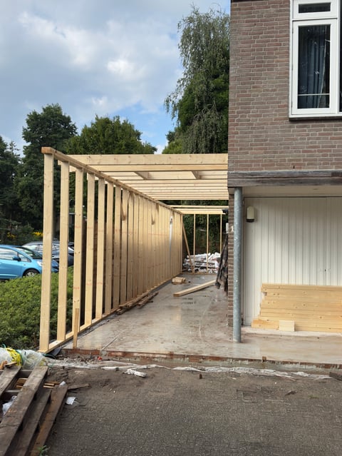 Wooden pergola structure with corrugated metal roof attached to brick house