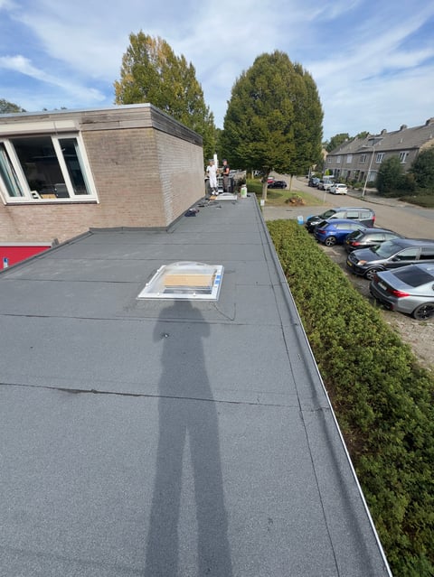 Rooftop view of a flat tar roof with a skylight